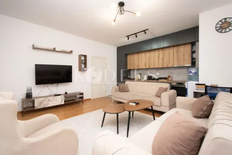 Dnevni boravak povezan sa kuhinjom u svijetlim tonovima sa garniturom i televizorom. - image 11