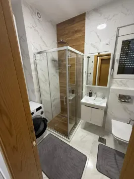 Moderno opremljeno kupatilo sa tuš kabinom i veš mašinom. - image 11
