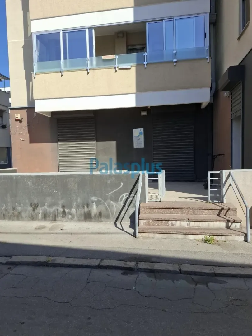 Entrance to the commercial space with stairs and roller shutters on the windows.