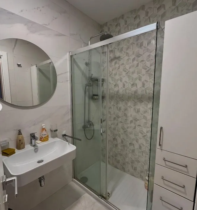 Modern bathroom with a sink, shower cabin, and mirror.