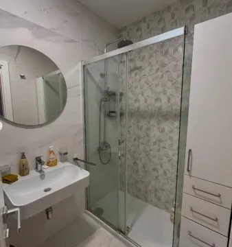 Modern bathroom with a sink, shower cabin, and mirror. - image 7