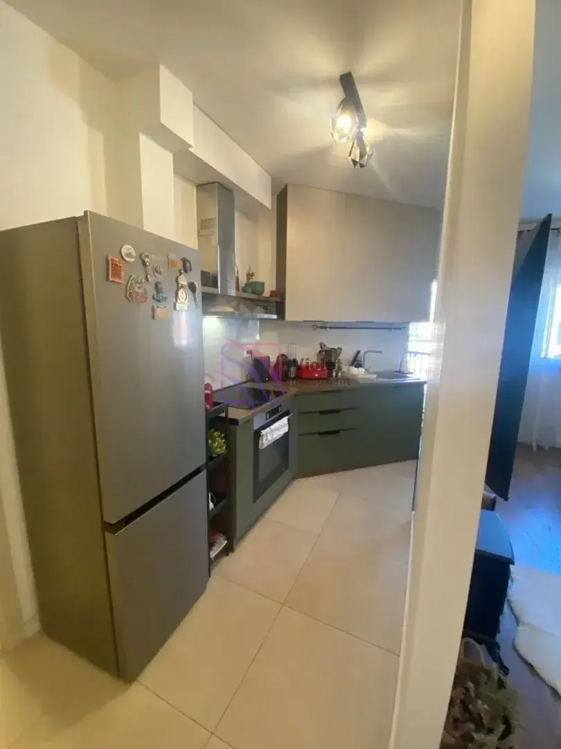 Manja kuhinja sa frižiderom i ugradnim elementima gledana sa ulaza.