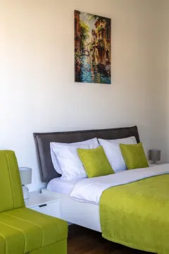 Uređena spavaća soba sa bračnim krevetom i zelenim detaljima. - image 2