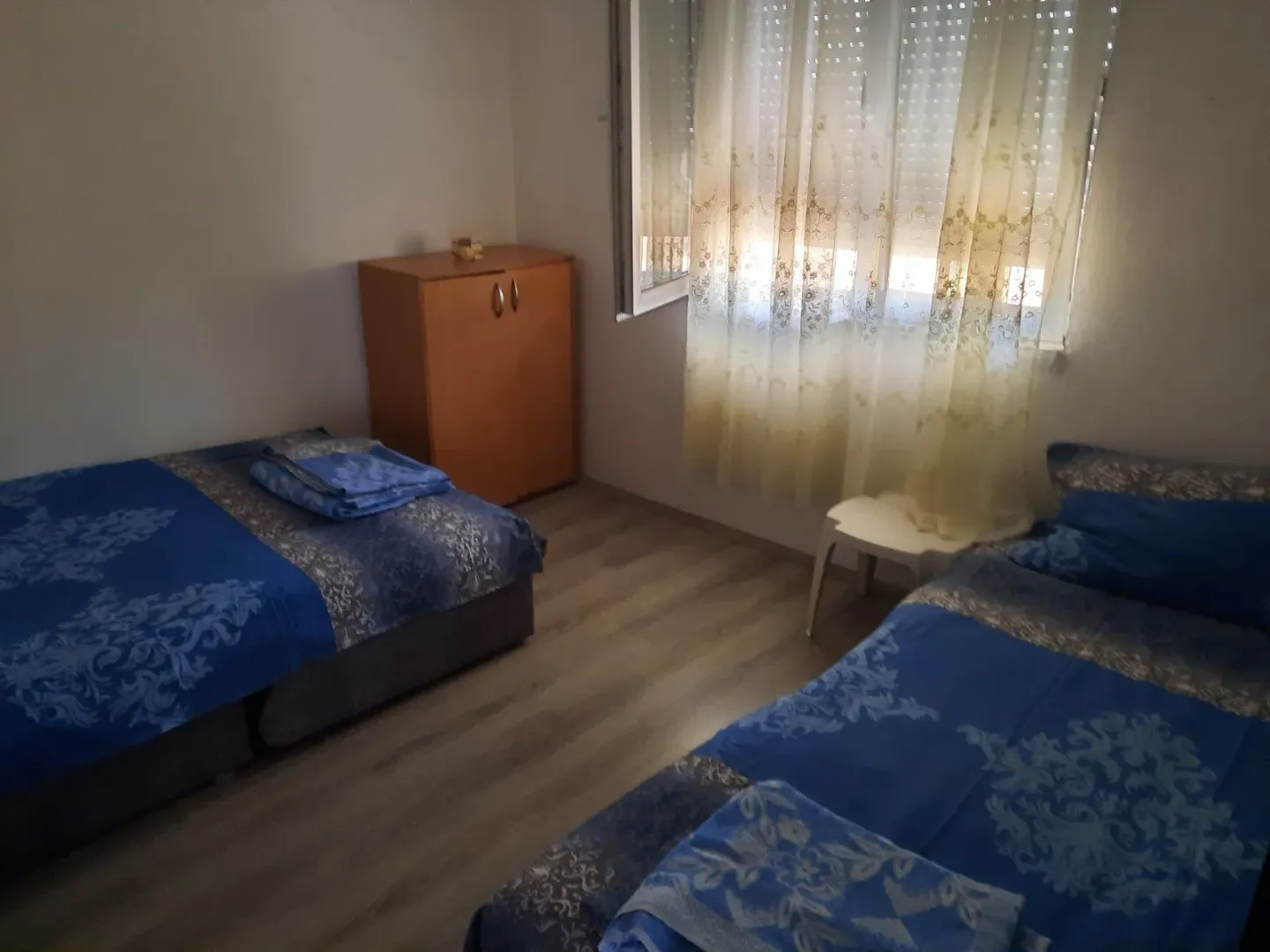 Bedroom with two beds, wardrobe, and a window.
