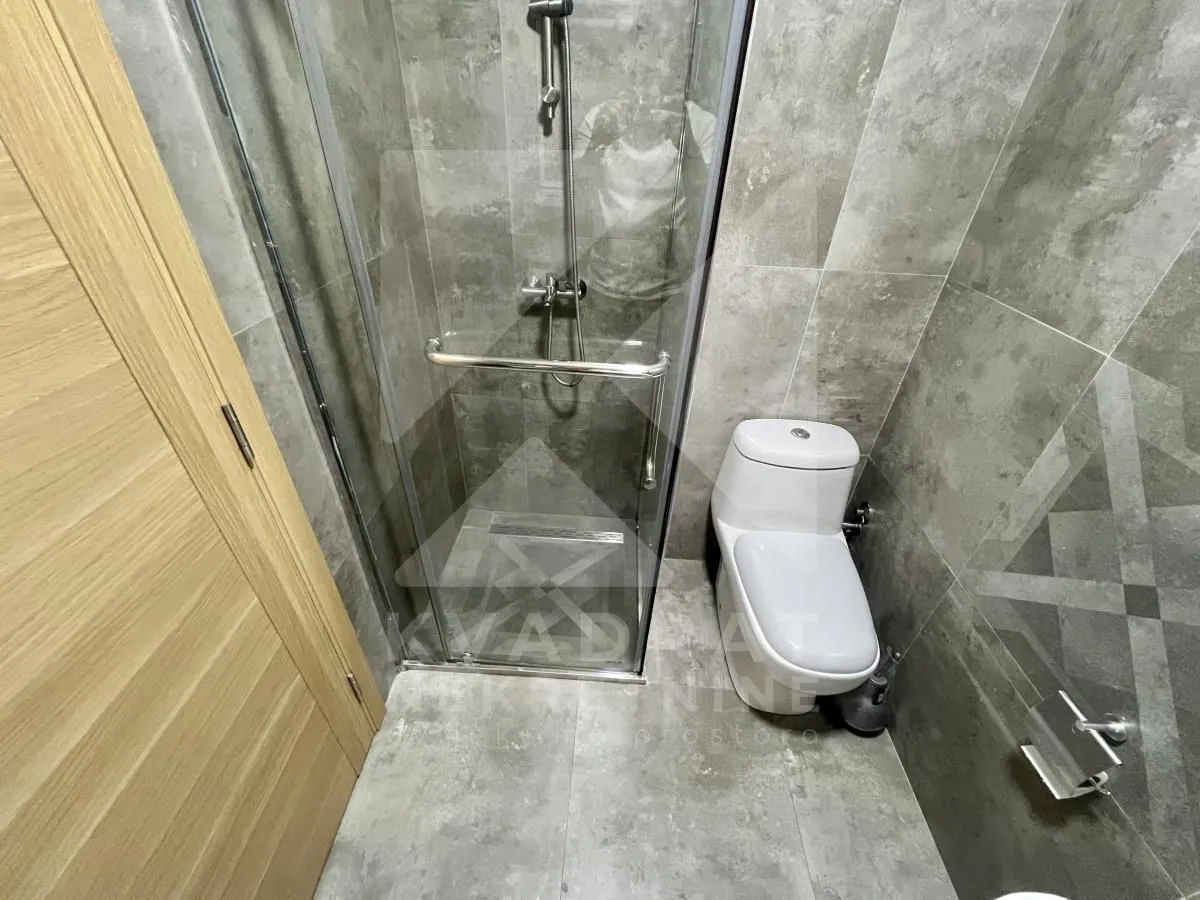 Manje kupatilo sa tuš kabinom i sanitarijama u sivoj keramici.