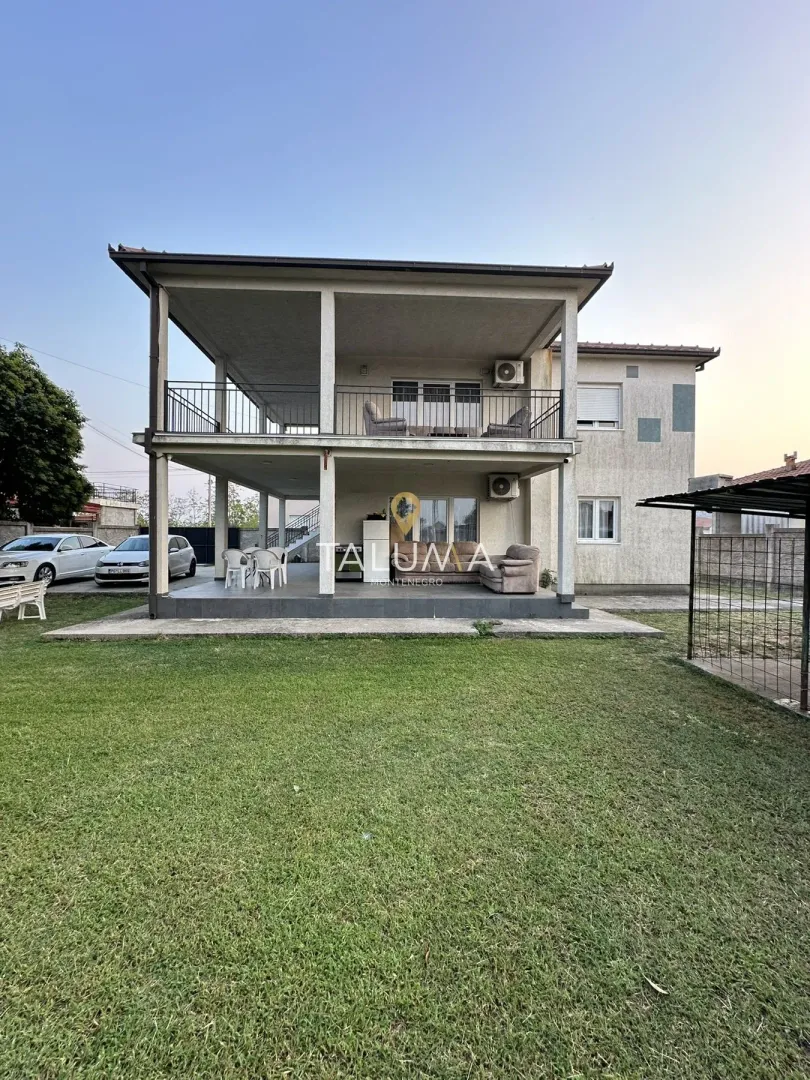 View of the yard and exterior of a two-story house with covered terraces.