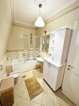 Bathroom with a bathtub, shower screen, washbasin, and white cabinet. - image 7