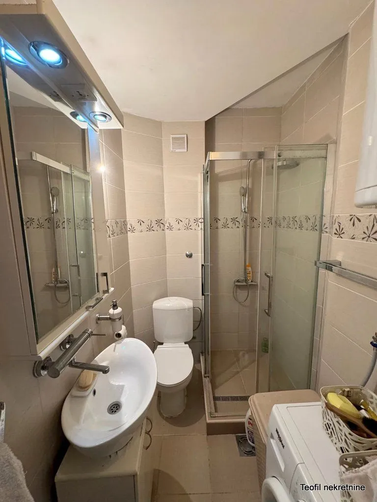 Compact bathroom with a shower cabin, sink, and toilet.