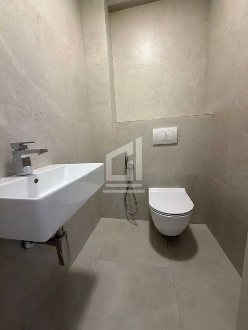 Manje kupatilo sa umivaonikom i ugradnom wc šoljom obloženo keramičkim pločicama.