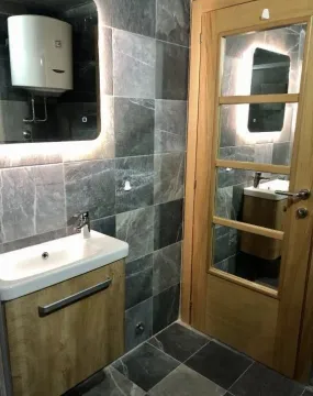 Modern bathroom with a sink, mirror, and wooden door. - image 8