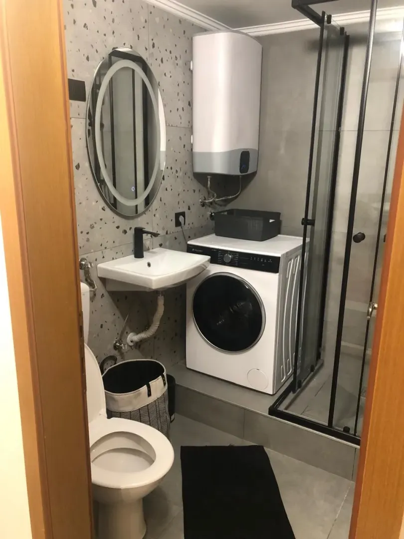 Small bathroom with a shower cabin, washbasin, washing machine, and water heater.