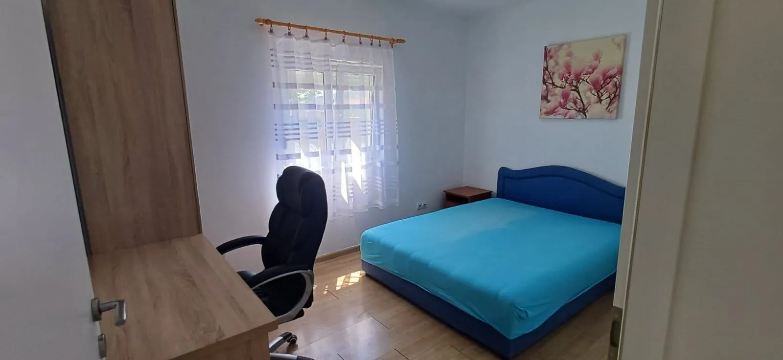 Furnished bedroom with a bed, desk, and window.