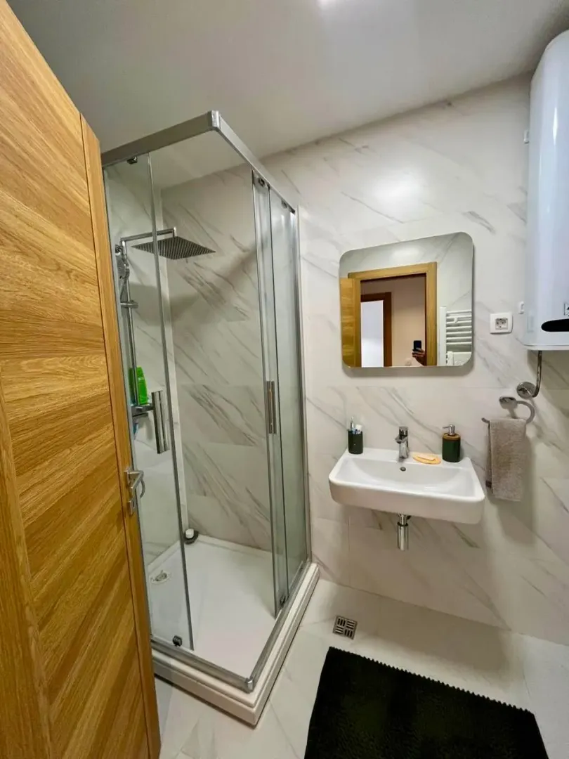 Modern bathroom with a shower cabin, washbasin, and mirror.