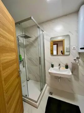 Modern bathroom with a shower cabin, washbasin, and mirror. - image 10