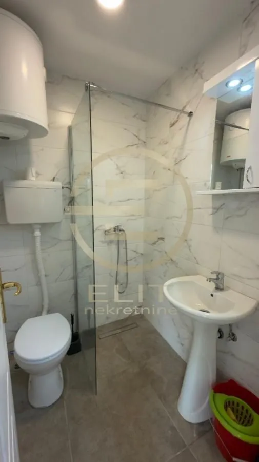 Moderno kupatilo sa tuš kabinom, umivaonikom i wc šoljom.