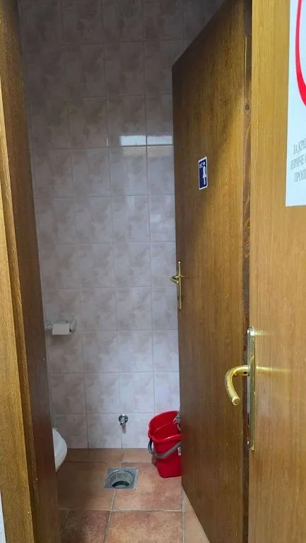 View of a small bathroom with tiles and a wooden door.