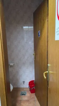 View of a small bathroom with tiles and a wooden door. - image 7