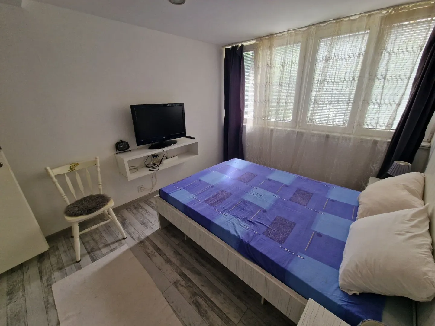 Bedroom with a double bed, window, and wall-mounted TV.