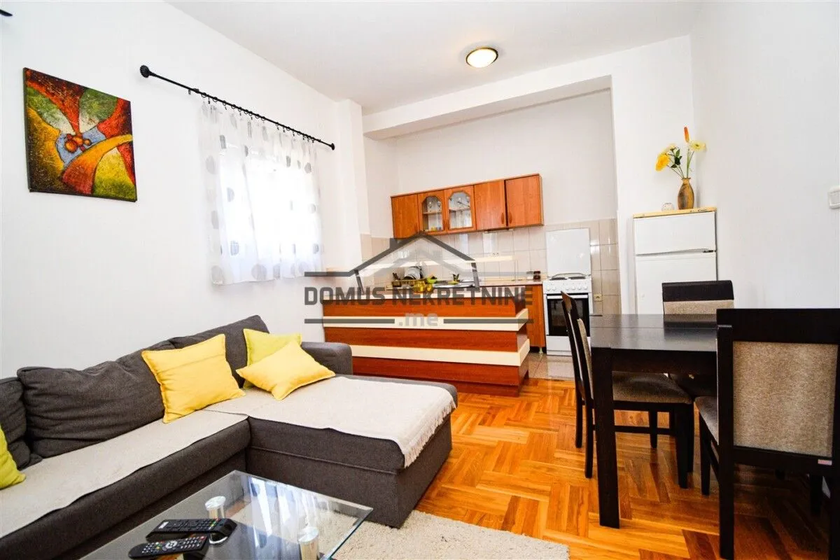 Living room with a sofa, dining area, and kitchen in the background.