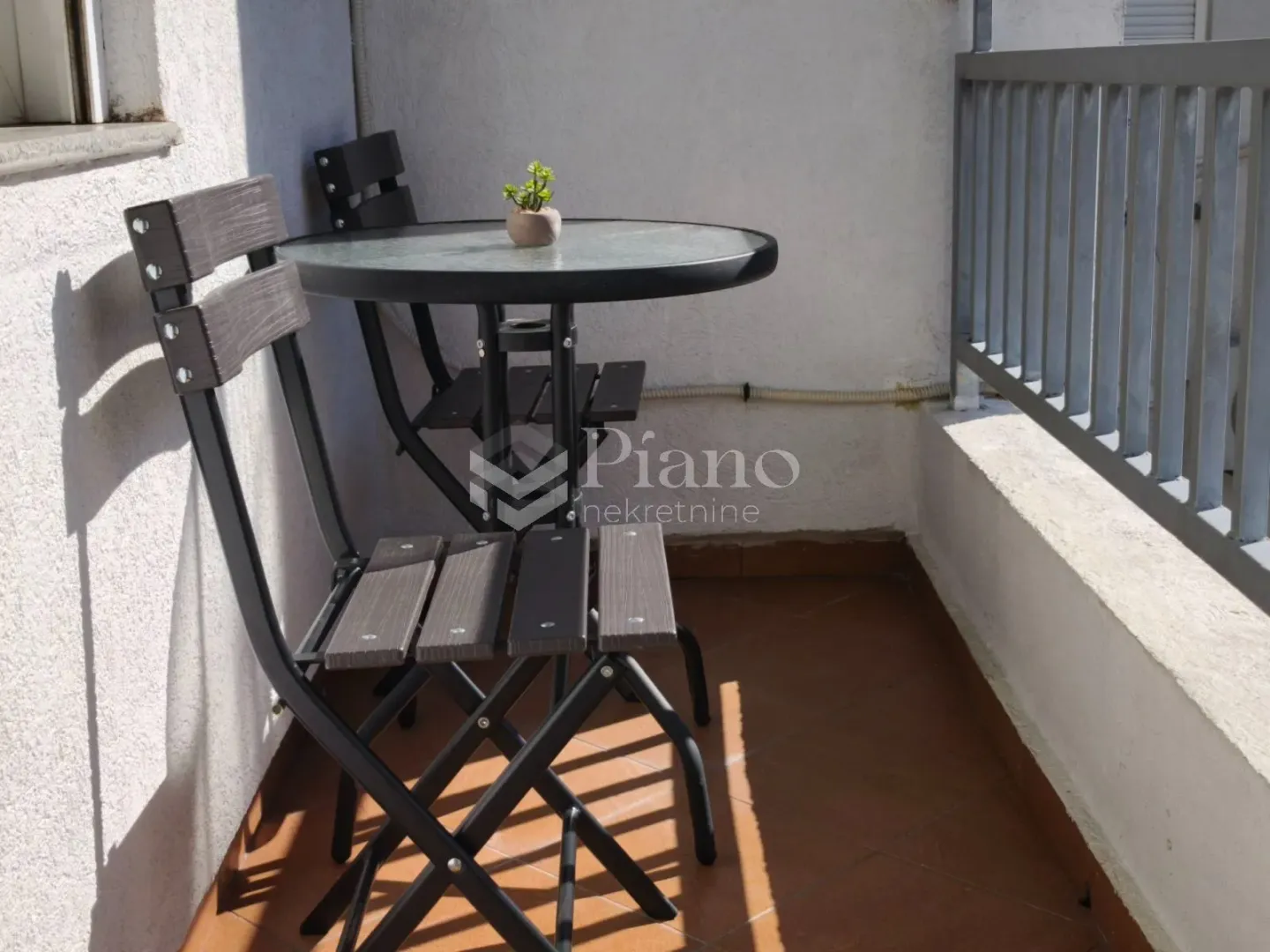 Manji balkon sa stolom i dve stolice.