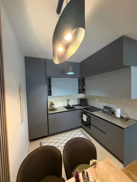 Modern kitchen with dark cabinetry and a dining table in the foreground. - image 10