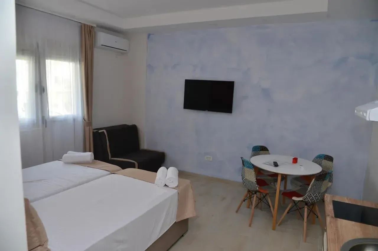 Bedroom with two beds, a dining table, and an air conditioning unit.
