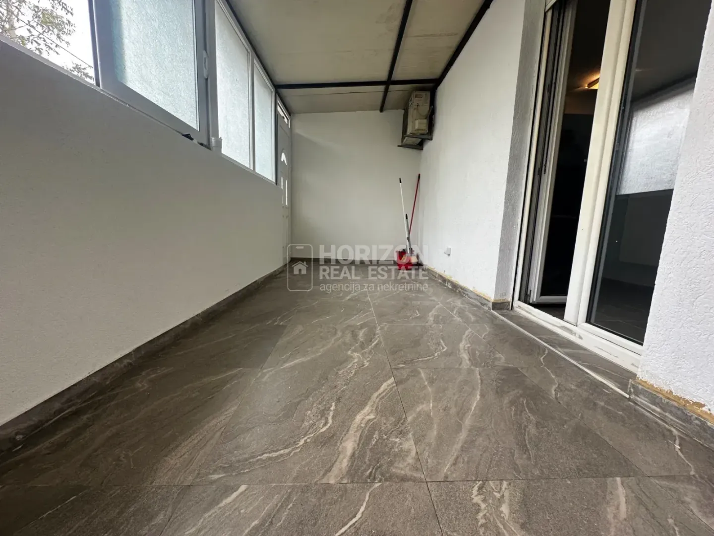 Covered terrace with ceramic tiles and glass windows.