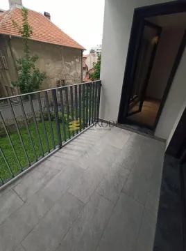 Small tiled balcony with a metal railing and a view of surrounding buildings and courtyard. - image 7