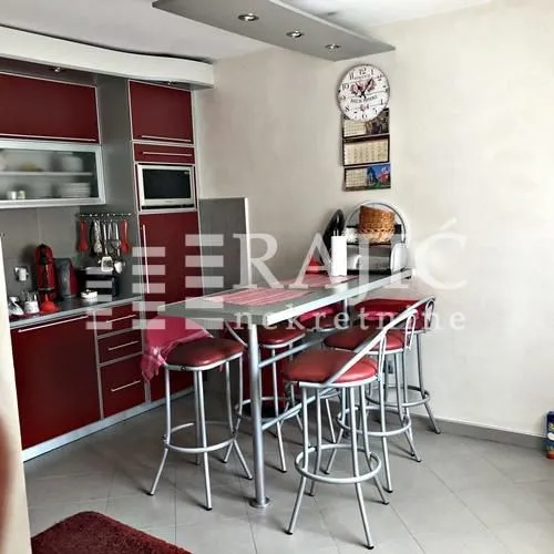 Kitchen with red cabinetry and a dining table with bar stools.