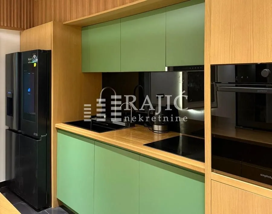Modern kitchen with green fronts and wooden elements.