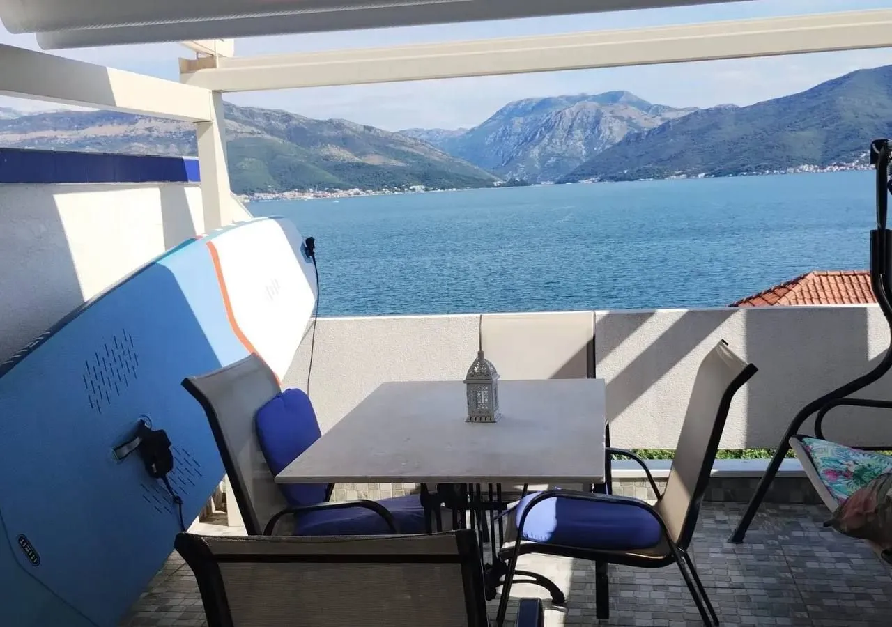 Namještena terasa sa stolom, stolicama i pogledom na more.