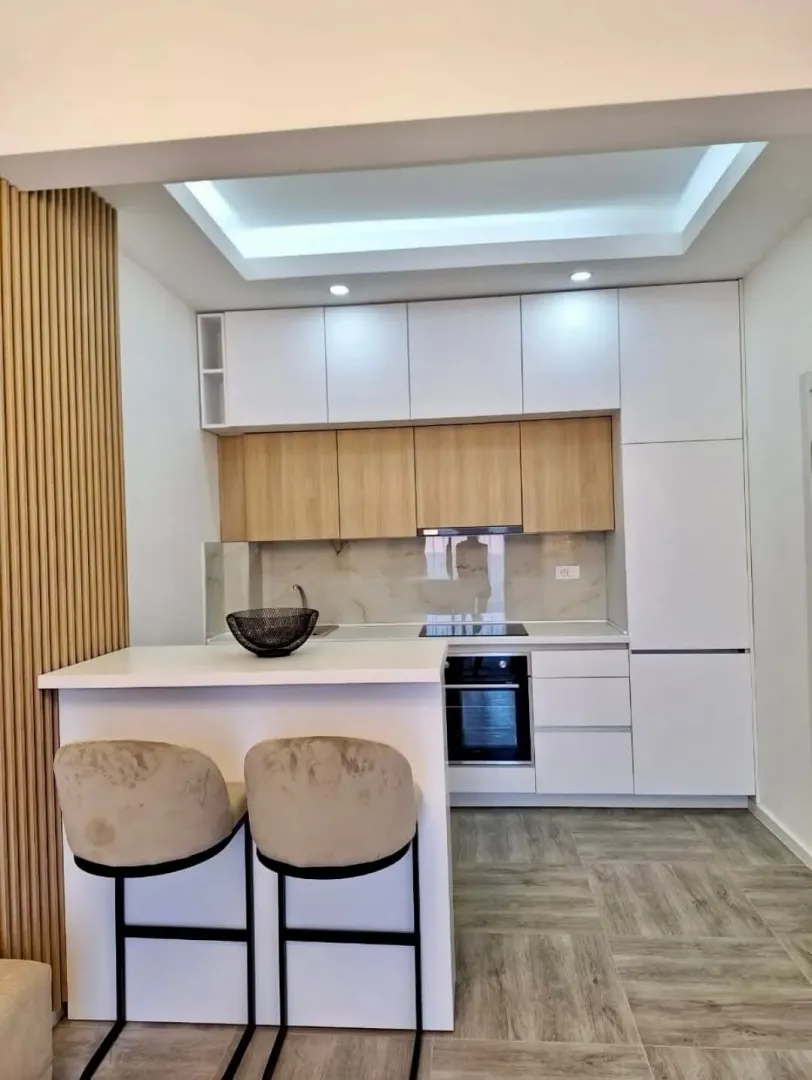 Modern kitchen with white and wooden cabinets and a breakfast bar with bar stools.