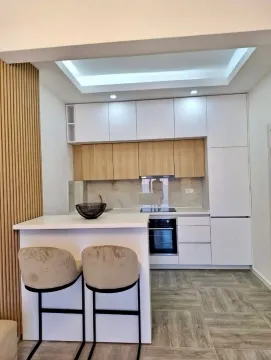 Modern kitchen with white and wooden cabinets and a breakfast bar with bar stools. - image 3