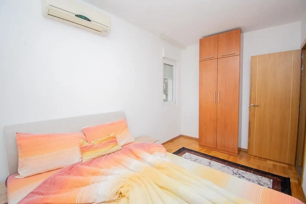 A bright bedroom with a wooden wardrobe and an air conditioning unit.
