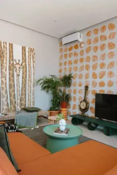 Dnevna soba uređena u modernom stilu sa zelenim i narandžastim detaljima i umjetničkim slikama na zidu. - image 6