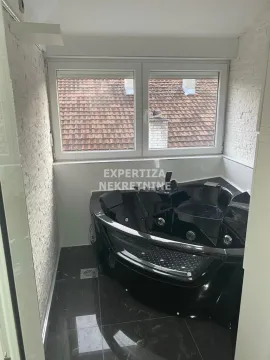 Bathroom with a black corner bathtub and a window. - image 11