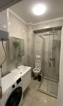 Savremeno opremljeno kupatilo sa tuš kabinom, umivaonikom i veš mašinom. - image 3