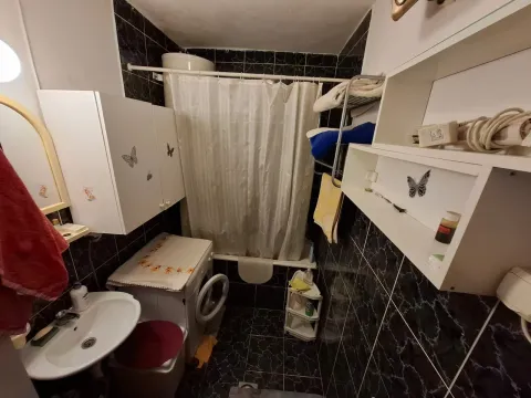 Kompaktno kupatilo sa kadom, umivaonikom, veš mašinom i bijelim zidnim elementima. - image 5