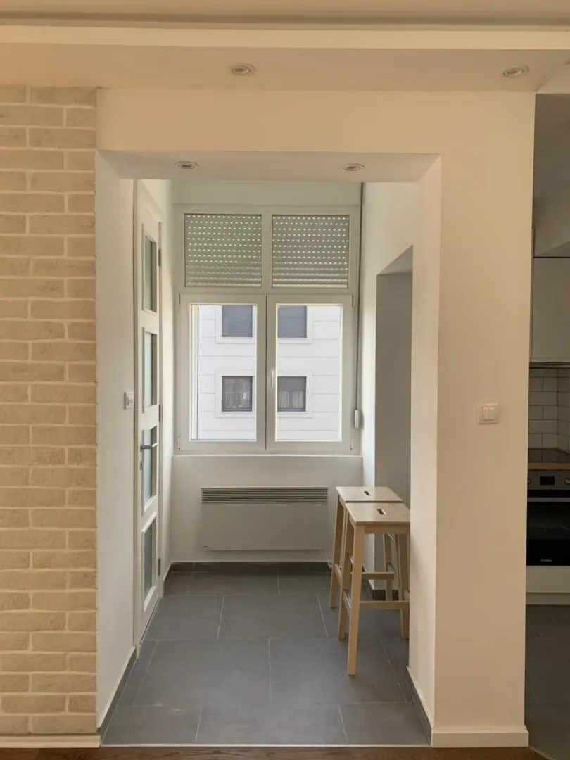 Glazed balcony space with a window and bar stools.