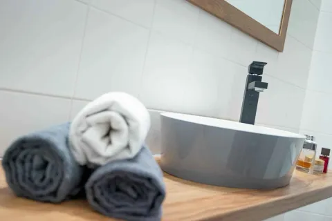 Detalj umivaonika sa urolanim peškirima u kupatilu. - image 10