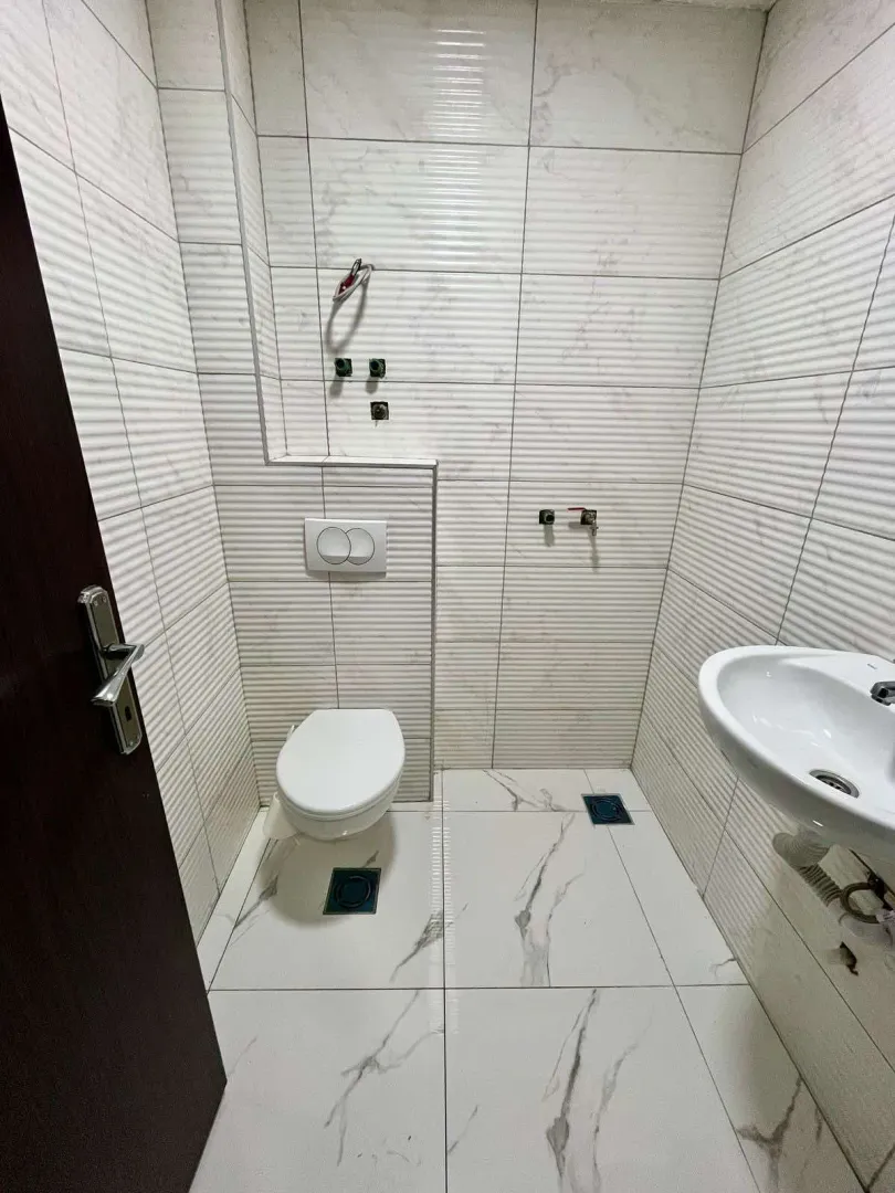 Small bathroom with light marble tiles, toilet, and sink.