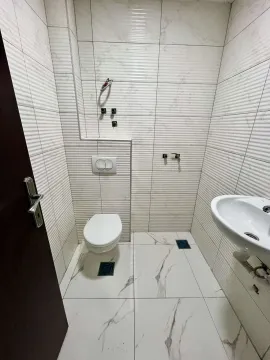 Small bathroom with light marble tiles, toilet, and sink. - image 4