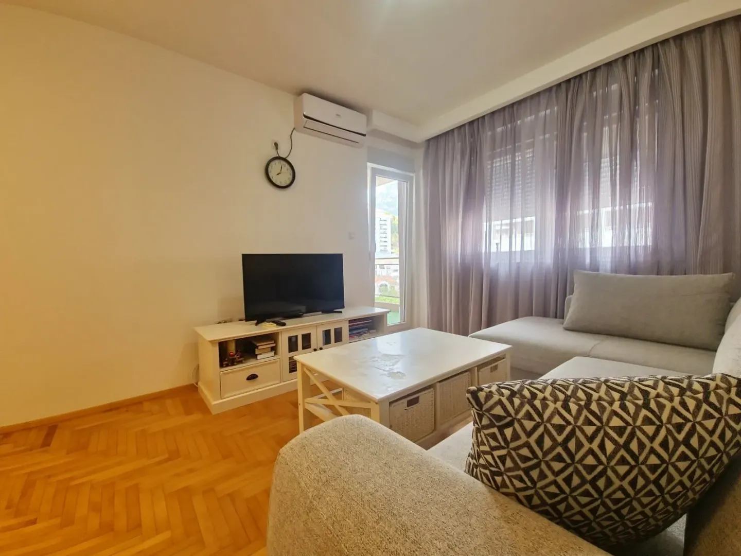 Living room with sofa, TV unit, and large window.