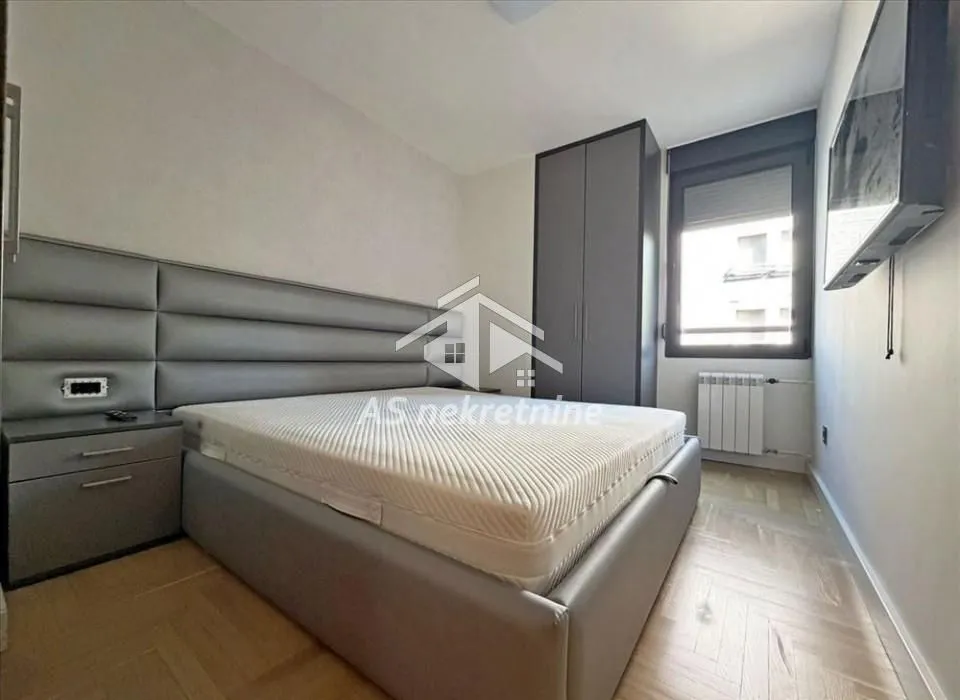 Furnished bedroom with a double bed, wardrobe, and window.