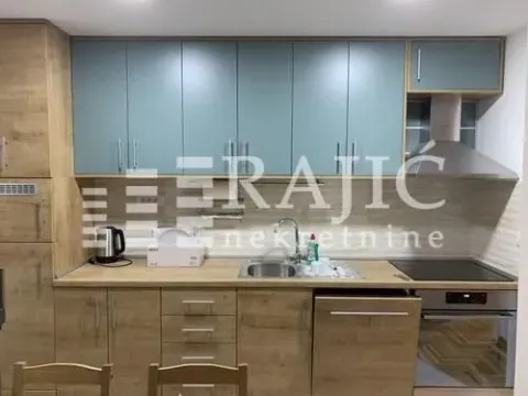 Equipped kitchen with wooden elements and blue upper cabinets. - image 4