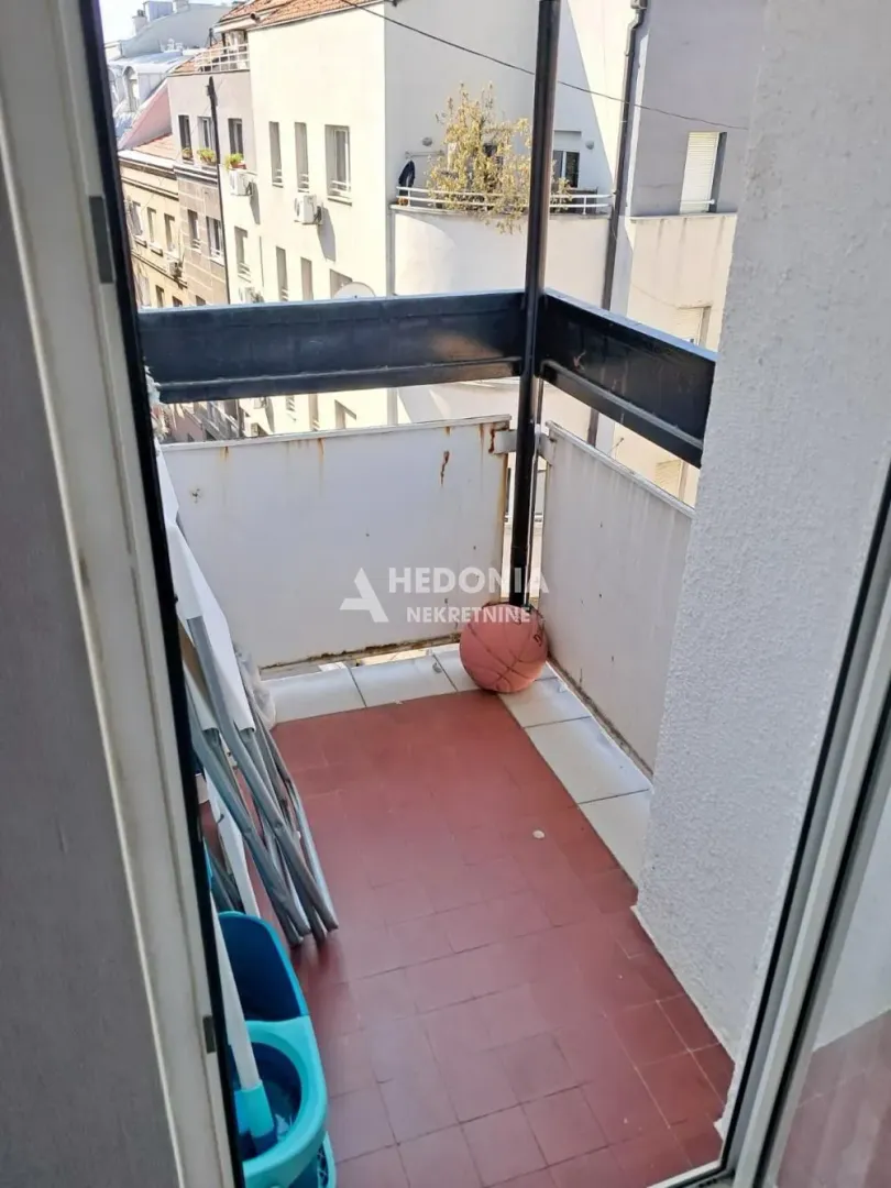 Manji popločani balkon sa pogledom na susedne zgrade.
