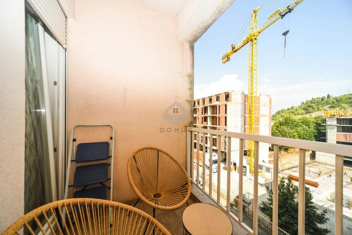 Small furnished balcony with a view of a construction site.