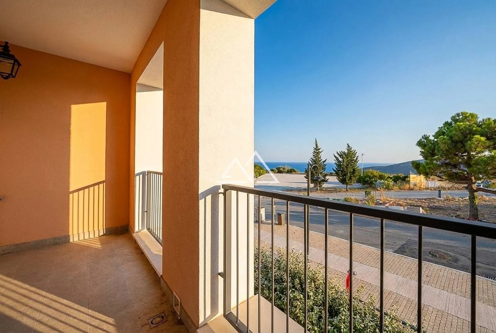 Natkriveni balkon sa metalnom ogradom i pogledom na okolinu.