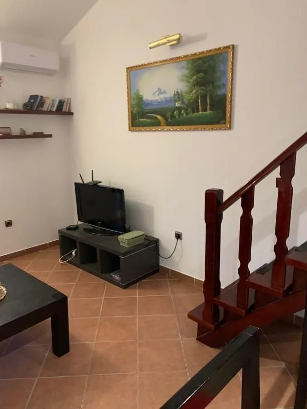 Living room with wooden staircase and a TV.