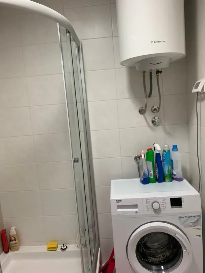 Bathroom with a shower cabin, a washing machine, and a water heater.